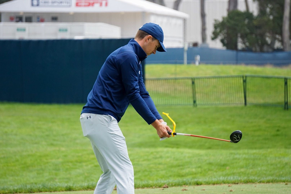 Professional golfer improving his golf swing with a teaching aid on the golf course.